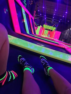 two people sitting on the ground in front of an indoor play area with neon lights