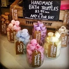 several jars filled with different types of soaps on top of a white table next to a sign that says handmade bath truffles