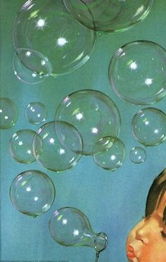 a young boy blowing soap bubbles into the air with his head tilted to the side