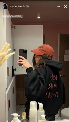 a woman taking a selfie in front of a bathroom mirror with her cell phone