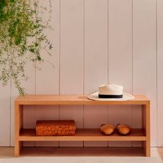 a hat and some bread sit on a shelf in front of a white painted wall