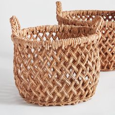 two woven baskets sitting side by side on a white surface