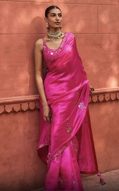 a woman in a pink sari leaning against a wall