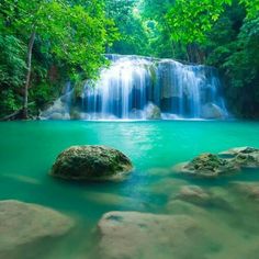 there is a large waterfall in the middle of some water with rocks and trees around it