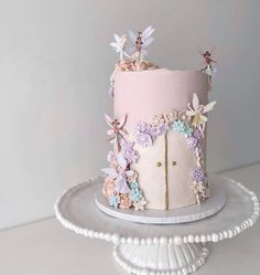 there is a pink and white cake with flowers on the top, sitting on a platter