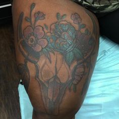 a woman's thigh with tattoos on her legs and flowers in the middle of it