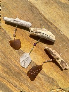 three necklaces are hanging on a rock with leaves and rocks in the foreground