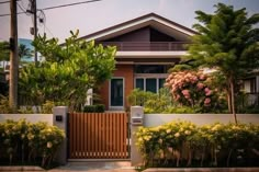 a house that is next to some trees and bushes in front of the fenced off area