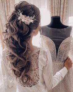 a woman standing next to a mannequin wearing a wedding dress with flowers in her hair