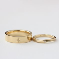 two gold wedding bands with small diamonds on them, one in the shape of a star