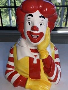 a close up of a ceramic clown talking on a cell phone