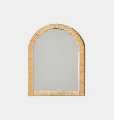 an arched mirror with a wooden frame on the front and back side, against a white wall