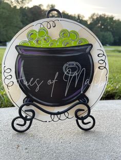 a black and white sign with green grapes in a pot on it's stand