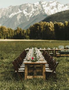 a long table set up in the middle of a field with mountains in the background