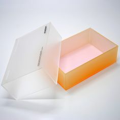 an orange and white box sitting on top of a white table next to another box