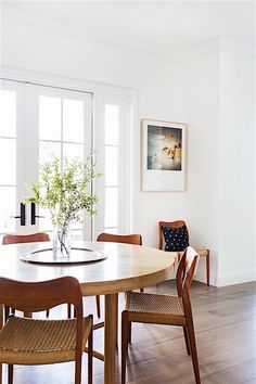 a dining room table with four chairs and a potted plant in the center on top