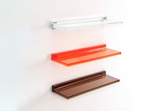 three glass shelves on the wall, one orange and one brown