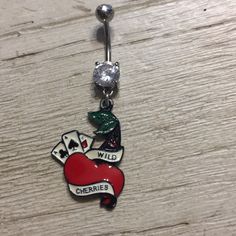 a red apple belly ring with a diamond in the center and wild cherries on it