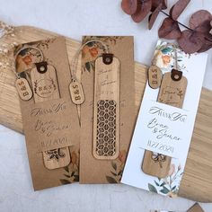 three wooden tags with flowers on them are sitting next to a card and some leaves