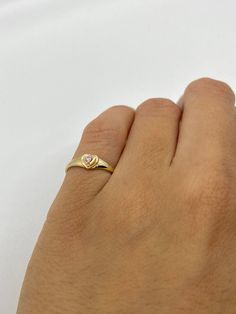 This cute small 14K gold heart signet ring is the perfect size for a baby, child, or pinky ring for women. The center stone is a simulated pink or white diamond (Cubic Zirconia). The ring is made of 100% 14K gold. It's a beautiful ring for a little girl or a gorgeous pinky ring. Ring pictured on a small child's hand and woman's 2 1/2 pinky finger Stamped 14K gold Cubic Zirconia Stone Small sized ring Visit us on Instagram @agoldmindjewelry for our custom jewelry designs and newest listings ▬ All Womens Pinky Ring, Dainty 14k Gold Tiny Heart Ring, Dainty Tiny Heart Ring In 14k Gold, Dainty Tiny Gold Heart Ring, Pinky Signet Ring Women, Dainty Heart Ring With Heart Charm, Dainty Heart-shaped Promise Birthstone Ring, Dainty Heart Shaped Birthstone Promise Ring, Dainty Heart Birthstone Promise Ring