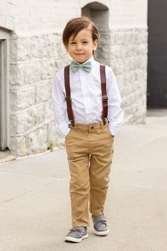 Boy dressed up in bow tie and suspenders Bowtie And Suspenders Wedding, Simple Ring Bearer Outfit, Boys Suspenders Outfit Wedding, Tan Bow Tie, Suspenders Outfit, Junior Groomsmen