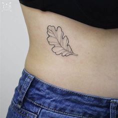 a woman's stomach with a leaf tattoo on it