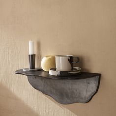 a shelf with two cups and a candle on it