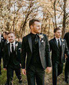 a group of men standing next to each other wearing black suits and white boutions