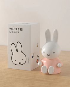 a white and pink rabbit figurine next to a box on a wooden table