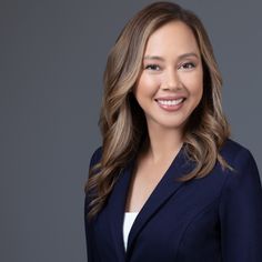 a smiling woman in a blue blazer and white shirt is posing for the camera