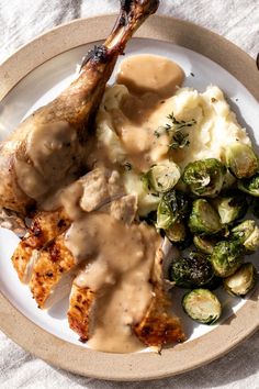 a white plate topped with chicken, mashed potatoes and brussel sprouts