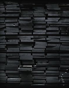 a large stack of black wooden planks stacked on top of each other in the dark