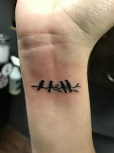 a small tattoo on the wrist of a woman with birds sitting on it's branches