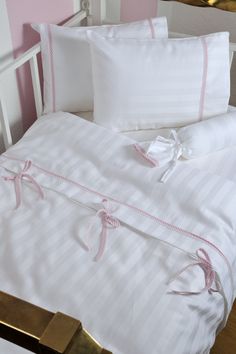 a bed with white and pink sheets, pillows and pillow cases on top of it