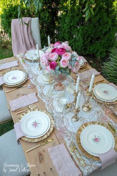 the table is set with pink flowers and gold place settings for an elegant dinner party