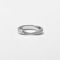 a white gold wedding ring on a plain surface