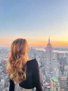 a woman standing on top of a tall building looking down at the cityscape