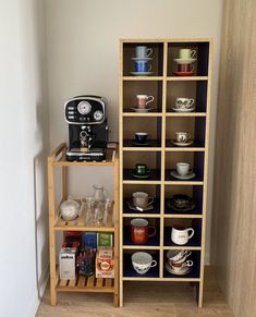 there is a coffee maker and shelves with cups on them in the corner of this room