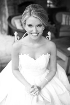 black and white photograph of a woman in a wedding dress sitting on a chair smiling at the camera