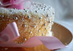 a close up of a cake with sprinkles and pink ribbon on a plate