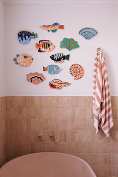 a bath tub sitting next to a bathroom wall with fish on it's side