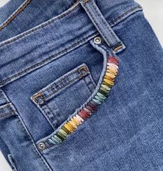 a pair of jeans with colorful beads in the back pocket and on the inside side