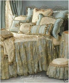 the bed is made with gold and blue comforters, pillows, and matching foot stools