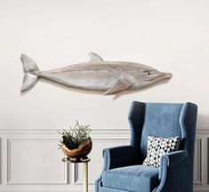 a living room with a blue chair and a fish wall hanging on the wall above it