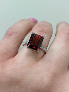 a woman's hand with a ring on it and a red stone in the middle