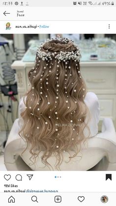 the back of a woman's head with long wavy hair and pearls on it