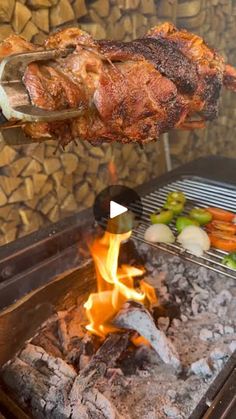 the meat is being grilled on the grill with tongs over it's flames