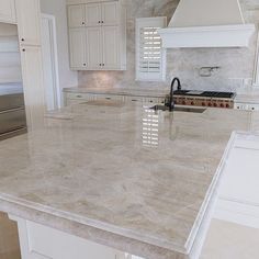 a kitchen with marble counter tops and white cabinets