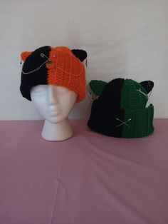 New beanie collection! Introducing the split cat beanies! This listing is for two of the seven new half black, half another color cat beanies with fun spooky charms and gold accessories! Available in orange and green with different charms and gold accessories placement. The white string and price tag is for in-person events which will be removed before sending. the paper part has care instructions and will remain on until it gets to you. Halloween Cosplay Beanie Hat, Black Beanie For Halloween, Themed Black Costume Hats For Winter, Black Knitted Hat For Halloween, Handmade Black Mini Hats For Winter, Handmade Black Mini Winter Hats, Handmade Halloween Beanie Hat, Halloween One Size Beanie Cap, Handmade Halloween Beanie