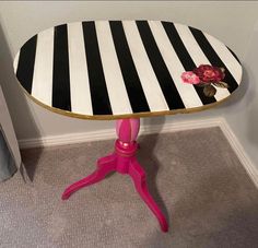 a pink table with black and white stripes on it, sitting next to a wall